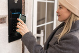 Smiling woman setting home security system with help of mobile application.
