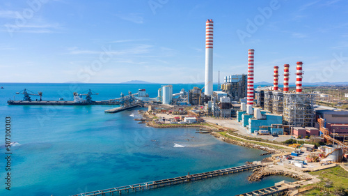 Aerial view on a large thermal power plant built along the coasts of the Mediterranean sea in Civitavecchia, near Rome, Italy. In the background the islands of the Tuscan archipelago.