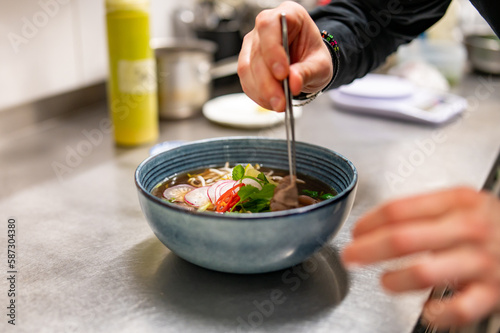 Close up of chef's hands cooking asian pho bo soup on restaurant kitchen
