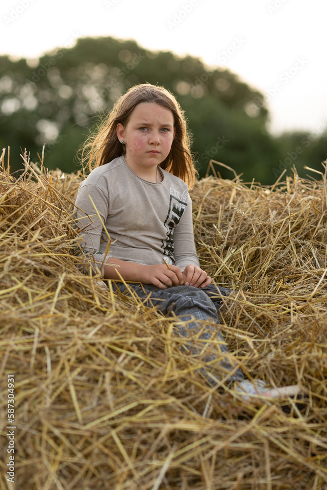 Sad pensive girl sitting on a haystack Sad pensive girl sitting on a haystack