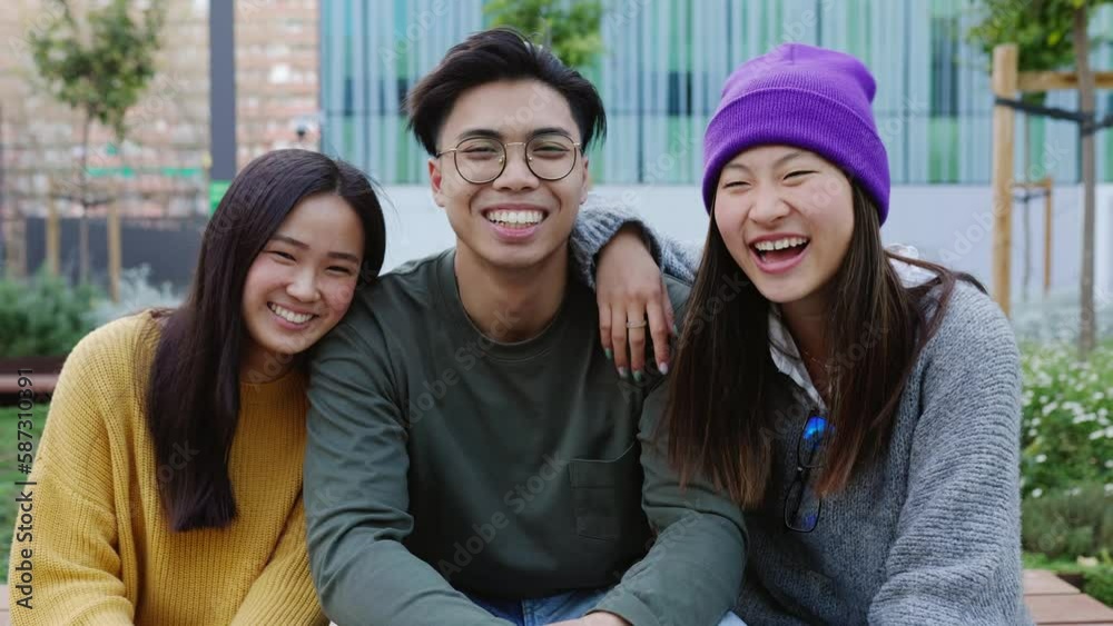 Young adult asian teenage people hugging each other while sitting together outdoors. Portrait group of three millennial student friends smiling at camera showing unity. Friendship lifestyle concept. Young adult asian teenage people hugging each other while sitting together outdoors. Portrait group of three millennial student friends smiling at camera showing unity. Friendship lifestyle concept.