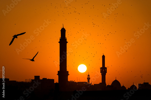 Foto Silhouette of mosque at sunset, seabirds flying