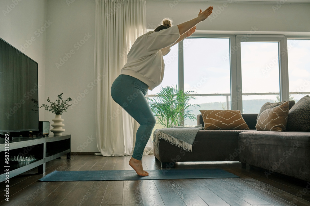 Woman doing online yoga at home. Female trener teaches asana in - obrazy, fototapety, plakaty 