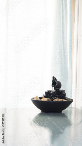 zen water fountain placed on top of a white wooden table next to a window