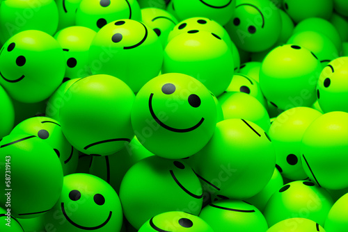 A large pile of small neon green balls with smiling faces painted on them
