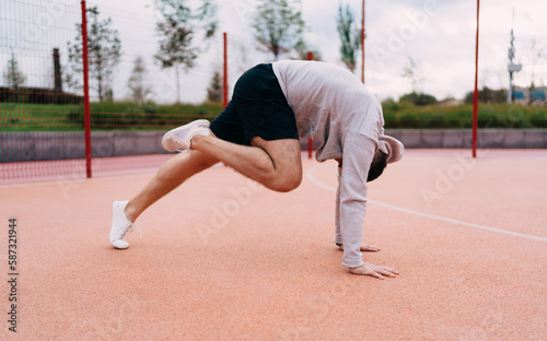 Muscular man exercising on sports ground