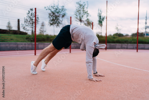 Anonymous sportsman doing back exercises on sports ground
