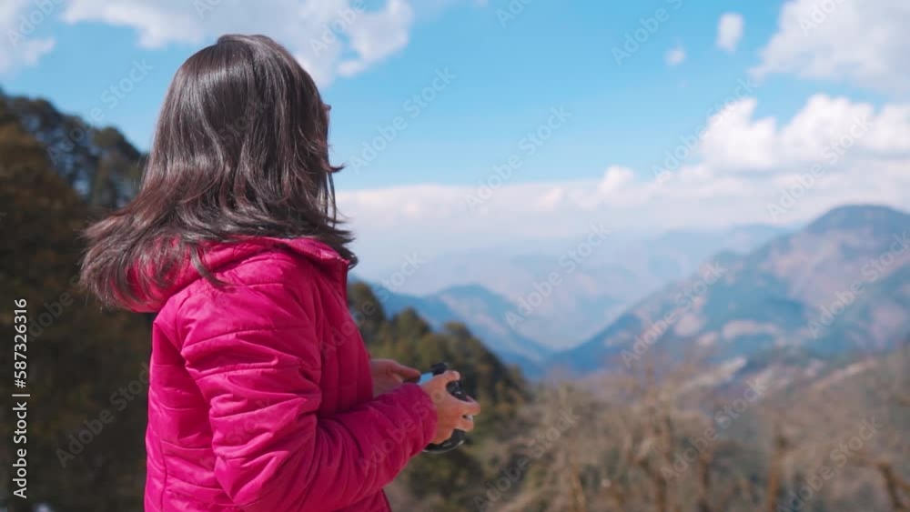 Young Indian woman photographer holding camera in hand and looking at the nature mountains view at Jalori Pass, Himachal Pradesh, India. Travel photographer on location for shoot. Young Indian woman photographer holding camera in hand and looking at the nature mountains view at Jalori Pass, Himachal Pradesh, India. Travel photographer on location for shoot.