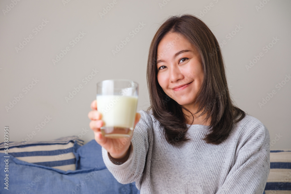 Portrait image of a young woman holding and showing a glass of fresh milk Portrait image of a young woman holding and showing a glass of fresh milk