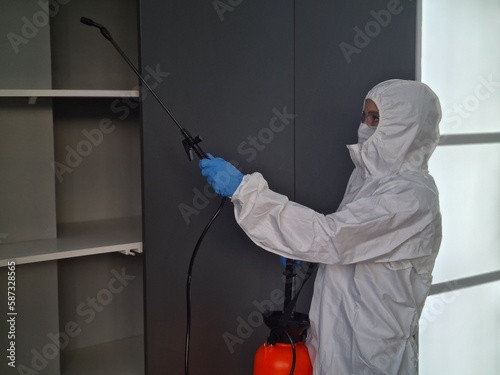 Person in protective suit and mask disinfects closet at home