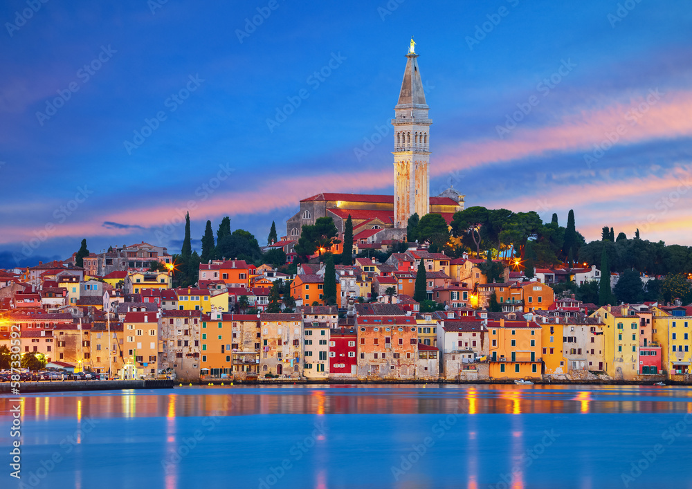 Early Morning in Rovinj, Croatia. Sunrise sky above vintage town at Istria peninsula Adriatic Sea. View from water old Mediterranean architecture buildings. Coastline and tower of Church Saint