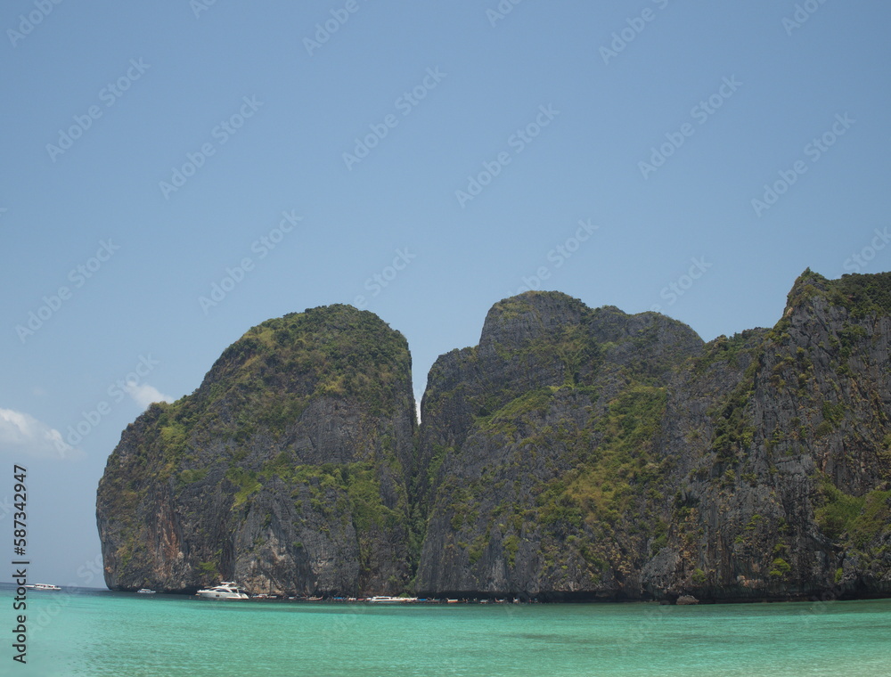 Beautiful beach -Maya Bay in Phi Phi Island. It is situated in Hat Noppharat Thara in Thailand. Quiet atmosphere beautiful sea, white sand beach, there are motor boats of tourists in the distance.
