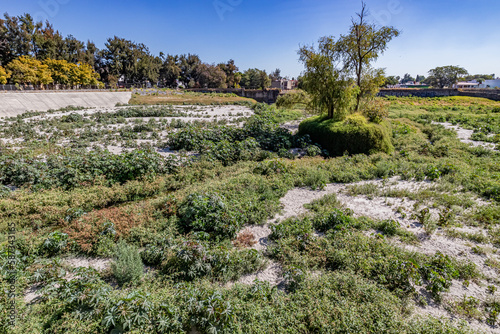 Panoramic view of dry Zoquipan dam against blue sky, wild vegetation, tributary of Atemajac river, green trees in background, paradise for birds in middle of city of Guadalajara, Jalisco Mexico photo