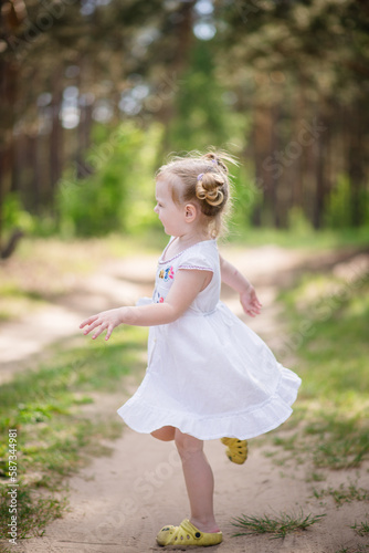 A girl in a white dress walks in the forest, spinning