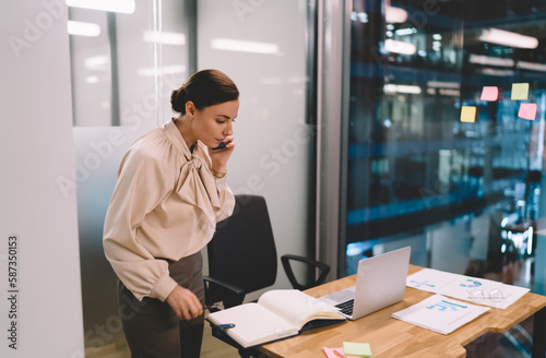 Serious woman working on project in office during phone call © BullRun