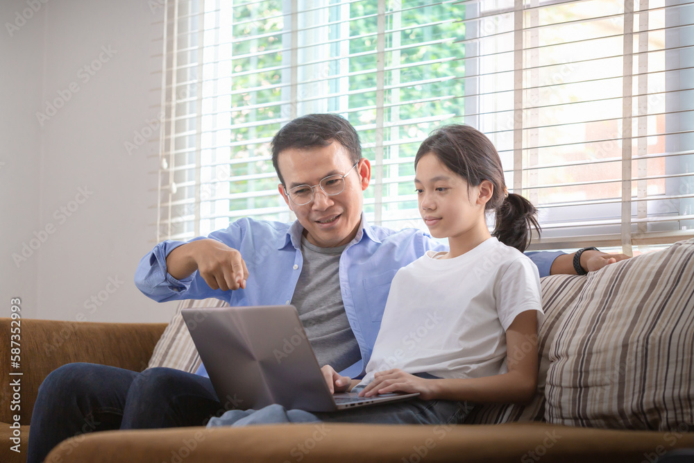 Asian father and daughter using laptop at home, People doing activities and family concepts Asian father and daughter using laptop at home, People doing activities and family concepts