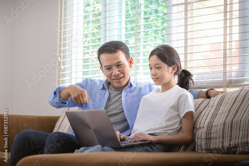 Asian father and daughter using laptop at home, People doing activities and family concepts