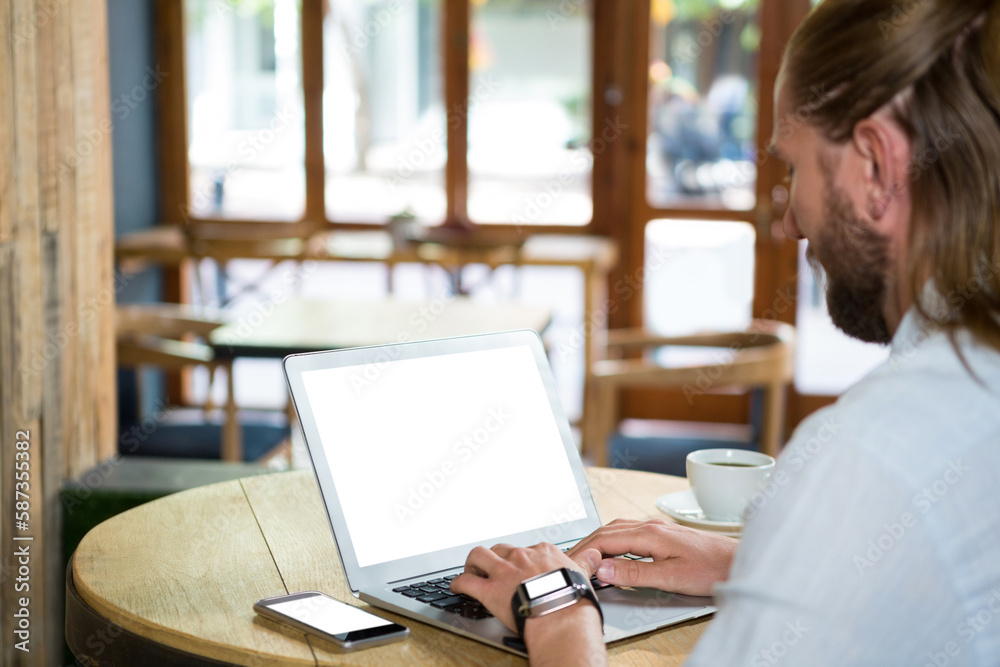 Side view of man using laptop in coffee shop Side view of man using laptop in coffee shop