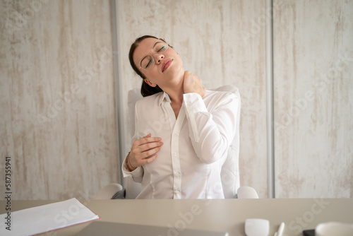 business woman having pain in the neck during work at office