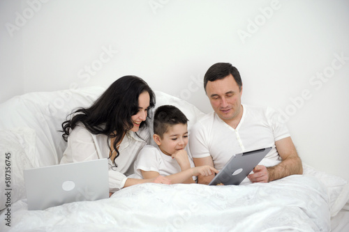 dad Mother and son under the blanket with digital tablet. kid dream online night video games at concept. family watching online video under covers with digital tablet. social media