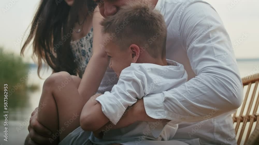 a happy young family of four has fun by the pond on a bench, children have fun with their father and mother. a happy young family of four has fun by the pond on a bench, children have fun with their father and mother.