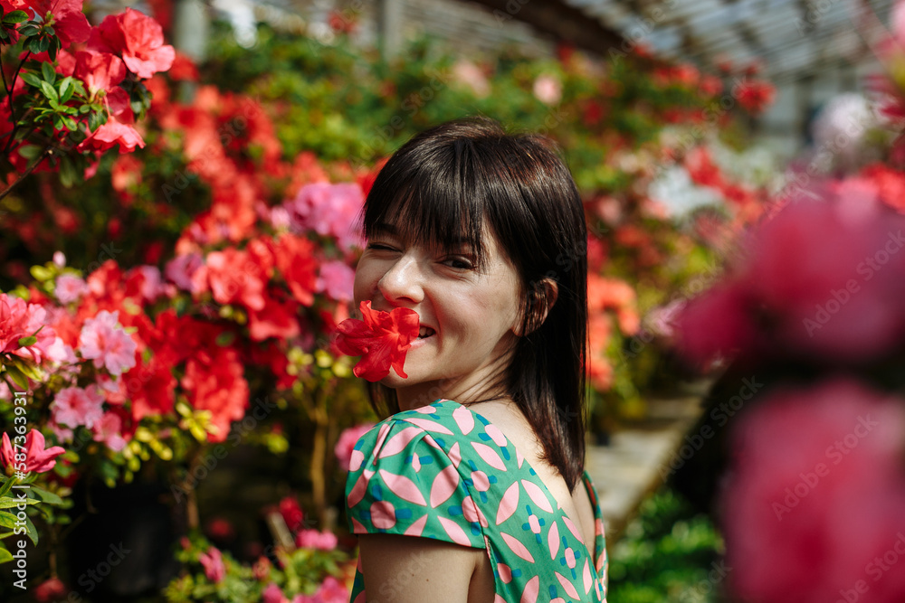A brunette in a green dress among blooming azaleas