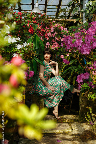 A brunette in a green dress among blooming azaleas