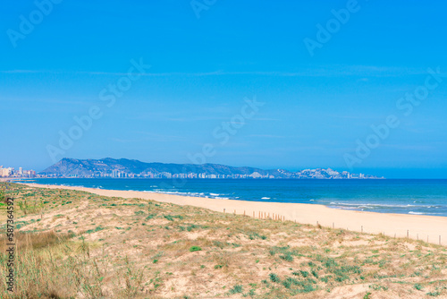 A beach with a view of the city of Cullera in the distance