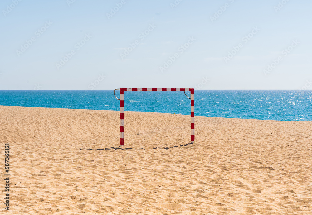 Soccer goal on a beach where you can see sky, sea and sand. Summer sports background.