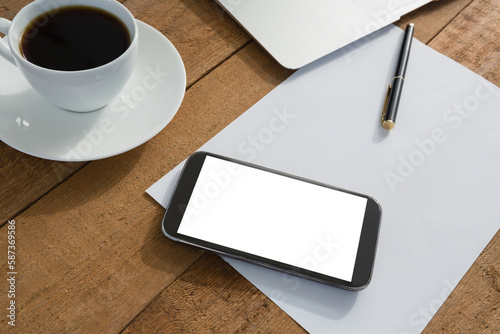 Laptop  mobile phone  black coffee  pen and paper on wooden plank