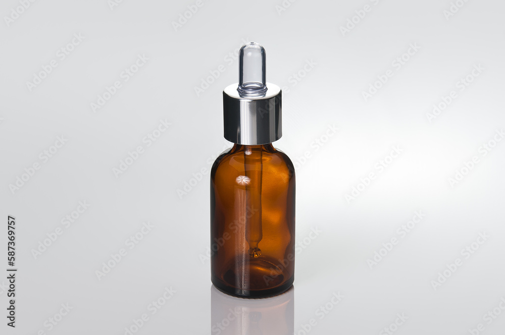 Glass brown transparent dropper bottle. Close-up, photo on a reflective surface.