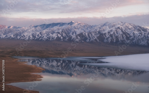 Beautiful snowy mountains are reflected in the water of lake at sunset