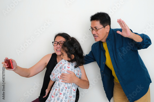 An Asian family with one daughter taking a wefie: smiling, happy expression. photo