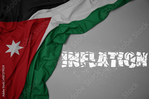 waving colorful national flag of jordan on a gray background with broken text inflation. 3d illustration