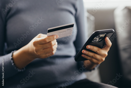 Close up of young woman holding credit card using smartphone online payment, home shopping, ecommerce, internet banking, spend money, finance, e-shop concept. © Witoon