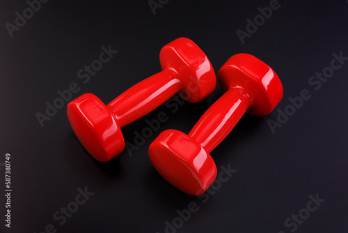 A pair of shiny dumbbells with bright highlights on a black background. Close-up. View from above.