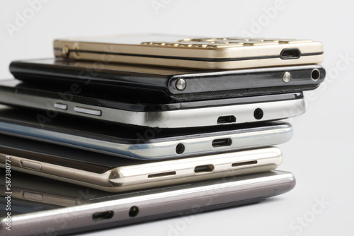 Many mobile phones of different generations and an electronic tablet on a white background. Modern digital gadgets. Micro USB and Type-c connectors for recharging