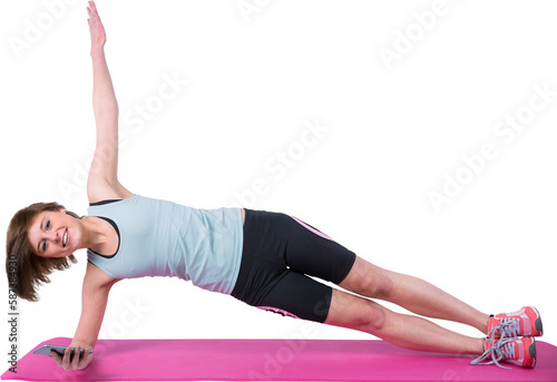 Pretty brunette looking at camera and doing side plank on exercise mat 
