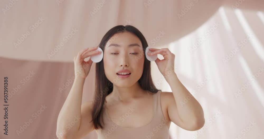 Beautiful Asian woman cleaning face skin. Pretty young female using cotton pad, smoothing skin and removing makeup with micelar water or lotion. Puring, washing, wiping. Skin care, beauty concept. Beautiful Asian woman cleaning face skin. Pretty young female using cotton pad, smoothing skin and removing makeup with micelar water or lotion. Puring, washing, wiping. Skin care, beauty concept.