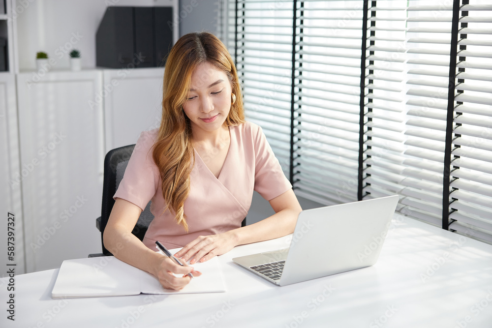businesswoman using laptop computer and writing on notebook in the office businesswoman using laptop computer and writing on notebook in the office