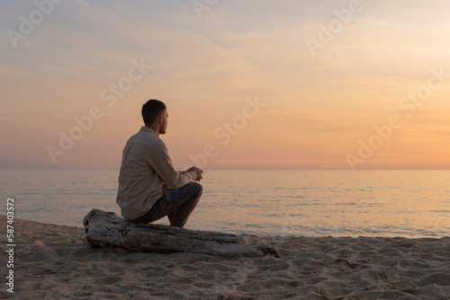 young man with shirt, watching the sunset on a beach