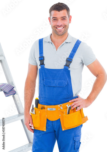 Happy male handyman in overalls standing by ladder