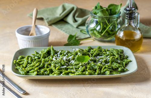 Spinach spatzle (or green spatzle) are the typical Tyrolean green dumplings or gnocchi on green plate with grated cheese and olive oil