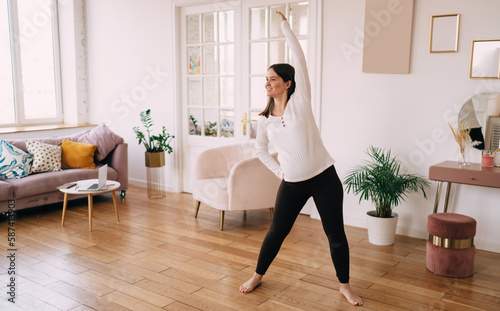 Cheerful prenatal woman doing workout in living room