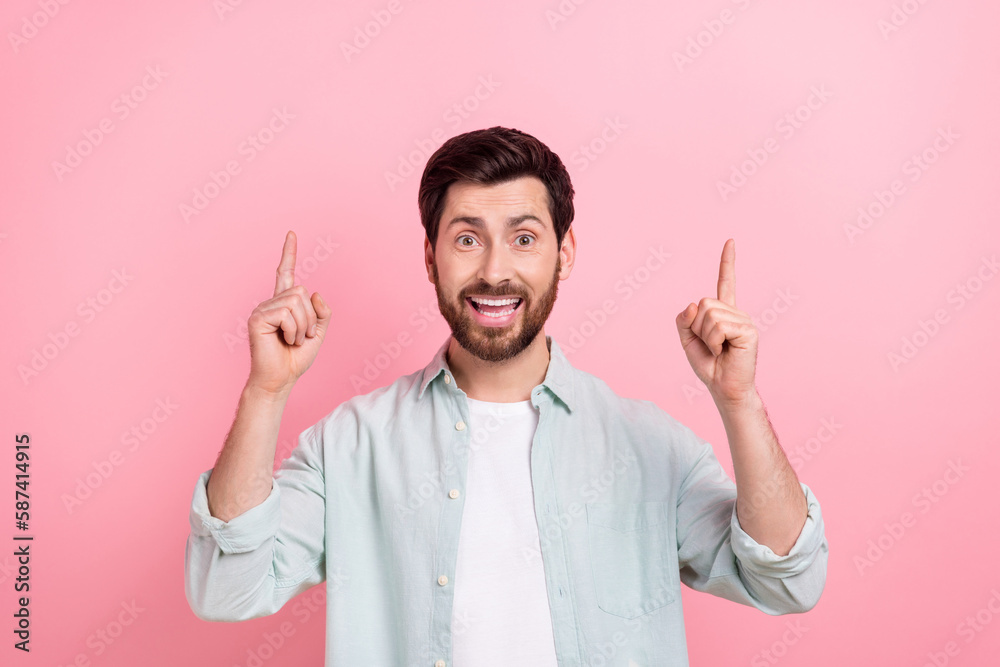 Photo portrait of attractive young man excited fingers point up empty space dressed stylish blue look isolated on pink color background Photo portrait of attractive young man excited fingers point up empty space dressed stylish blue look isolated on pink color background