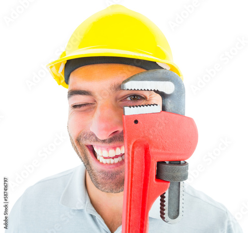 Cheerful handyman looking through monkey wrench