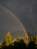 Rainbow on cloudy sky with mountain peaks in background