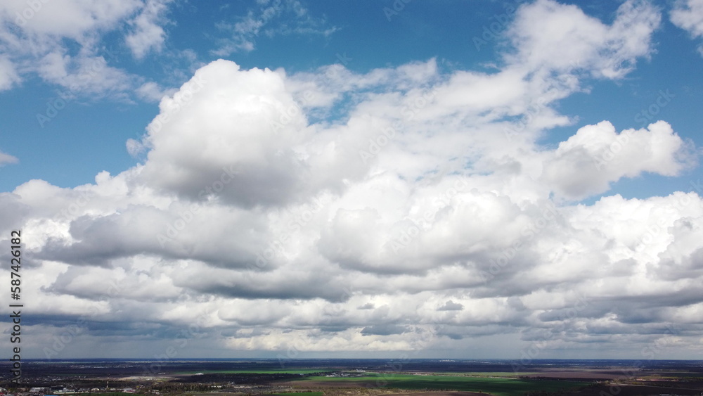 Fast movement of white cumulus clouds in blue sky during strong wind during day. Timelapse. Aerial drone view. Panoramic natural background. Rain. Rainy cloudy weather. Cloudscape. Scenic landscape. Fast movement of white cumulus clouds in blue sky during strong wind during day. Timelapse. Aerial drone view. Panoramic natural background. Rain. Rainy cloudy weather. Cloudscape. Scenic landscape.