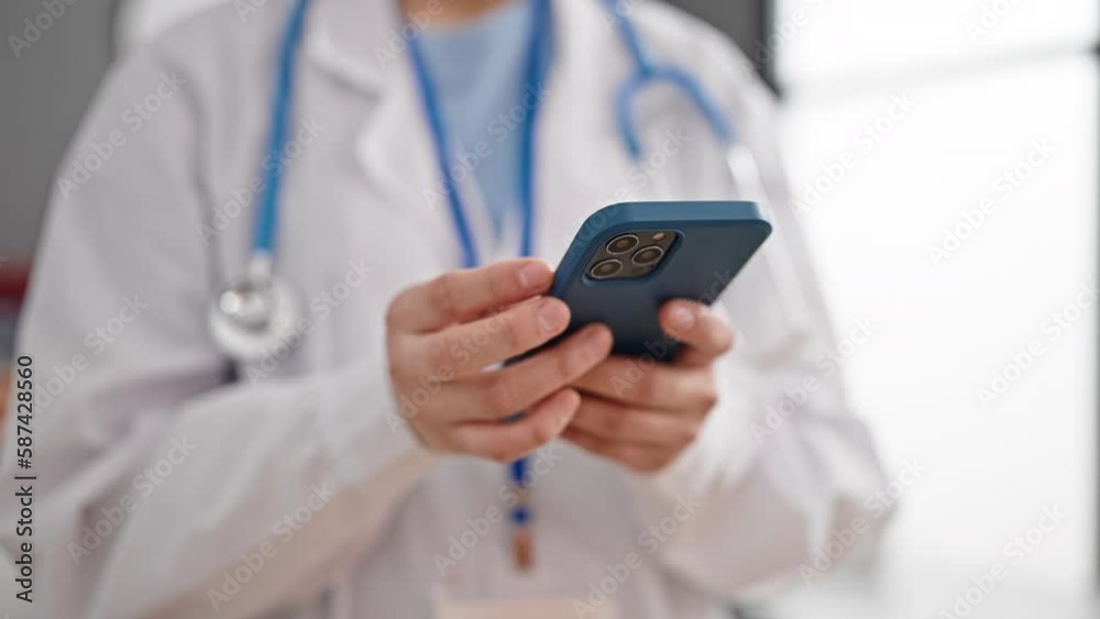 Young beautiful hispanic woman doctor using smartphone at clinic