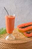 Indian papaya smoothie, lassi on gray background. Freshness cold beverage of yogurt, water, spices, fruits and ice. Popular beverage in India and Sri lanka. Vertical format.